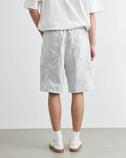 Person wearing light gray shorts and white shoes on a plain background