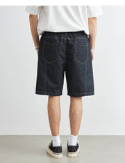 Person wearing black denim shorts on a plain background