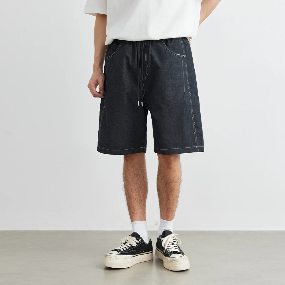 Person wearing black denim shorts with a white background