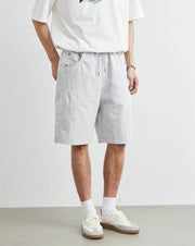 Person wearing a white t-shirt and light gray shorts on a plain background