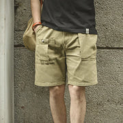 Person wearing beige shorts and a black shirt against a textured wall.