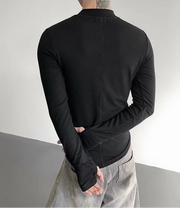 Person wearing a black long-sleeve shirt with a gray background
