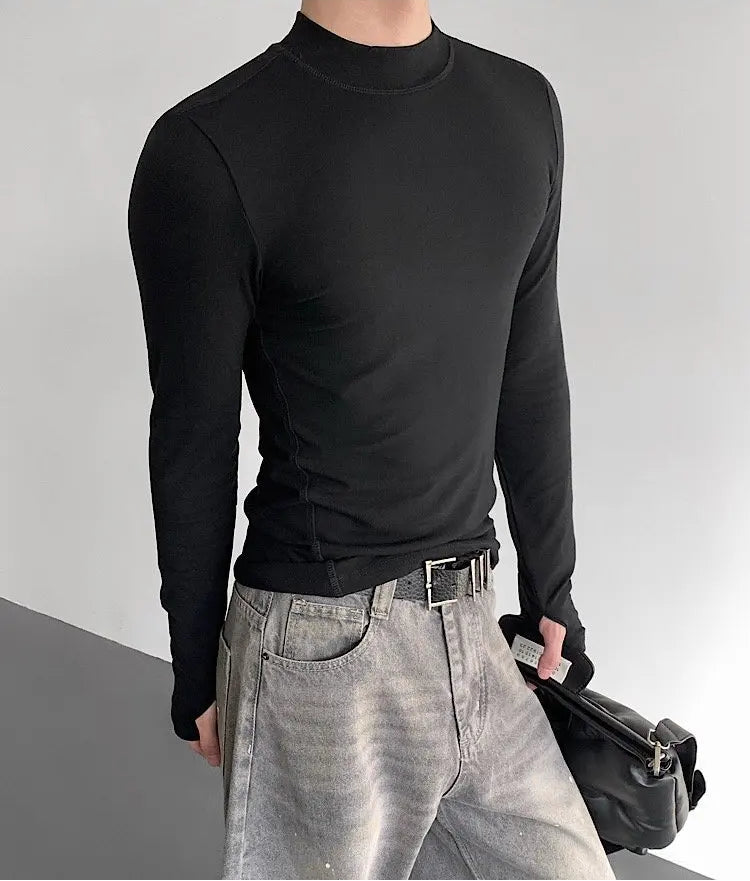Person wearing a black long-sleeve shirt and gray pants against a plain background