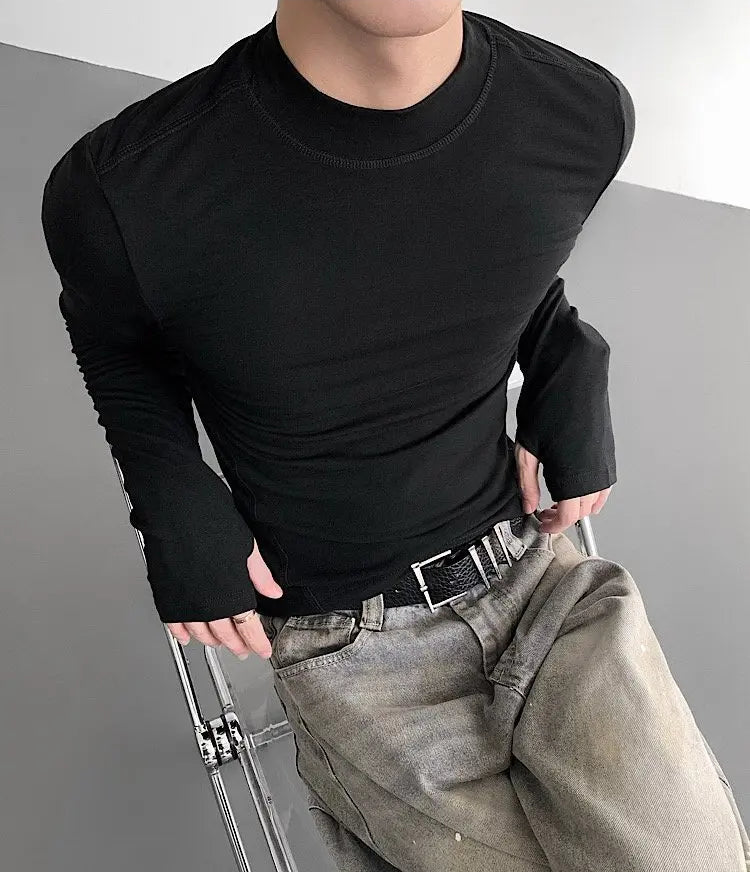Person wearing a black long-sleeve shirt and light gray pants on a gray background