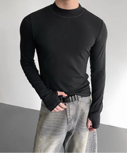 Person wearing a black long-sleeve shirt and gray jeans against a neutral background