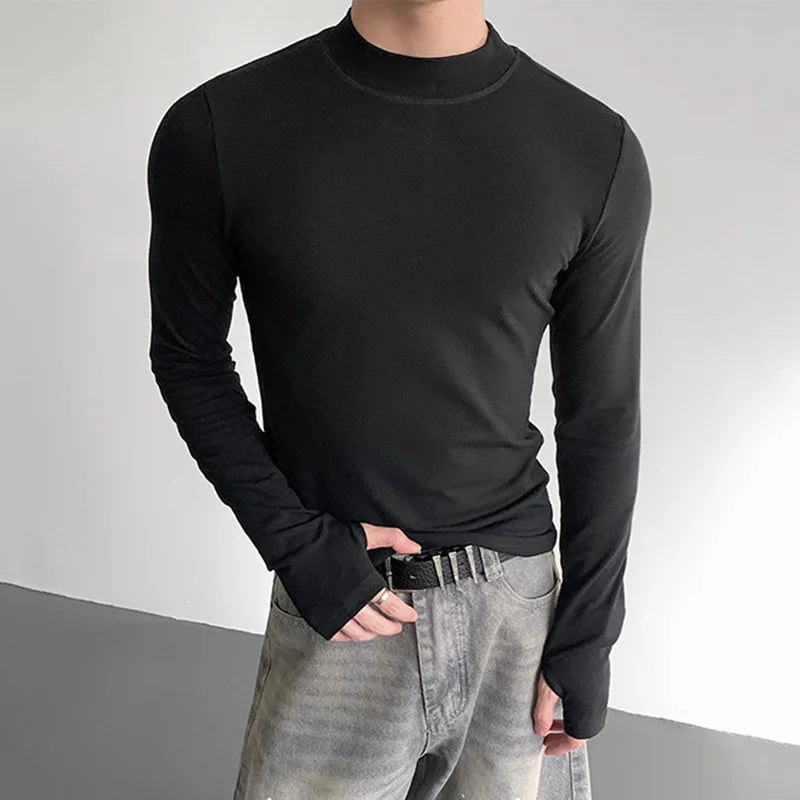Person wearing a black long-sleeve shirt and light gray pants on a plain background