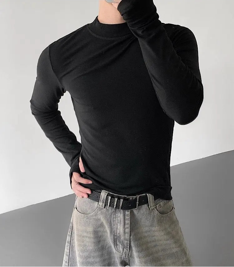 Person wearing a black long-sleeve shirt and gray pants against a neutral background