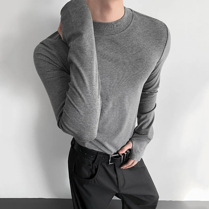 Person wearing a gray long-sleeve shirt and black pants against a white background