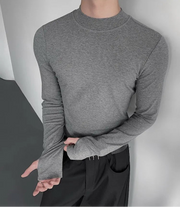 Person wearing a gray long-sleeve shirt against a neutral background