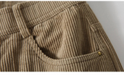 Close-up of a brown corduroy fabric with a button, on a white background.
