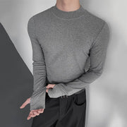 Person wearing a gray long-sleeve shirt against a gradient background