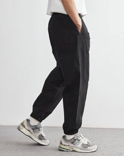 Person wearing black pants and gray sneakers on a plain background