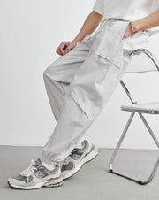 Person wearing light gray pants and sneakers sitting on a chair with a minimal background