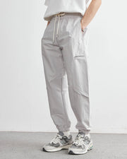 Person wearing gray cargo pants and white sneakers on a plain background