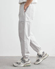 Person wearing light gray pants and sneakers on a white background