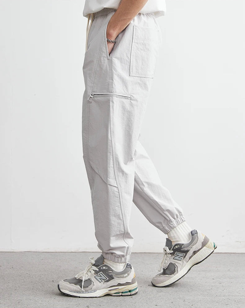 Person wearing light gray pants and sneakers on a white background