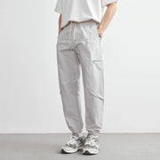 Person wearing light gray jogger pants and white sneakers on a plain background