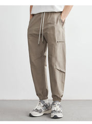 Person wearing beige cargo pants with a white background