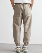 Person wearing beige pants and white sneakers on a plain background