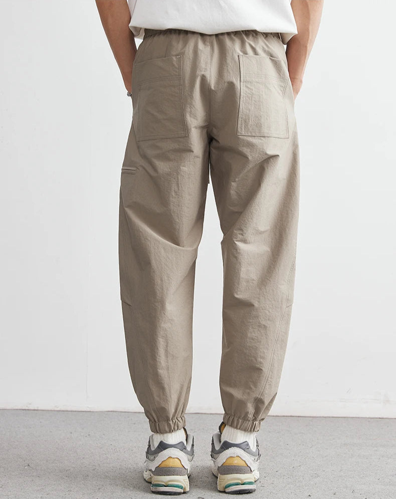 Person wearing beige pants and white sneakers on a plain background