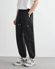 Person wearing black cargo pants and white sneakers on a plain background