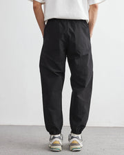 Person wearing black pants and a white shirt against a plain background
