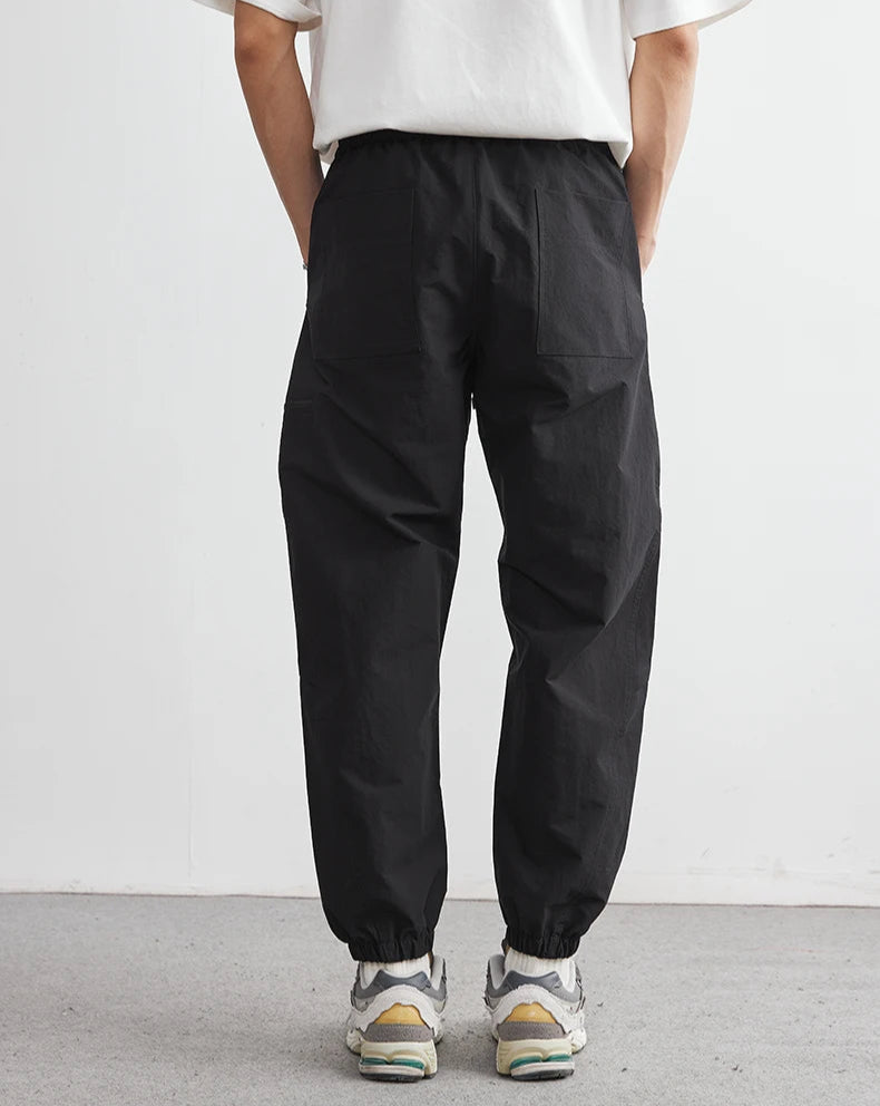 Person wearing black pants and a white shirt against a plain background