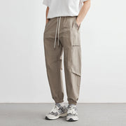 Person wearing brown cargo pants and white sneakers on a plain background