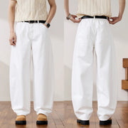 Two views of a person wearing loose white wide-leg pants with a black belt, paired with a cream striped shirt and tan shoes, shown against an indoor wall and wood floor.