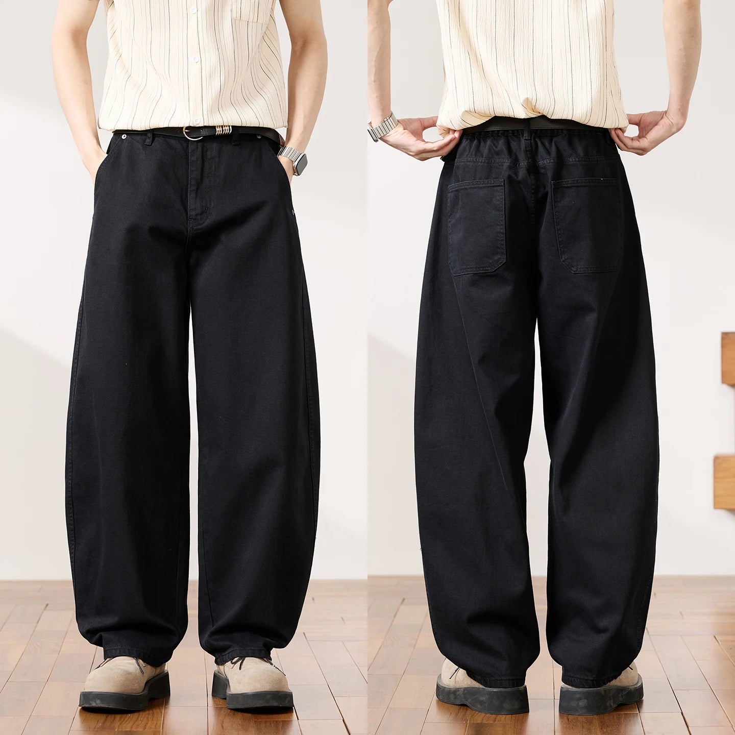 Two views of a person modeling loose black wide-leg pants with a relaxed straight-to-sweatdrop silhouette, paired with a cream striped shirt and beige shoes, shown against a white wall and wood floor.