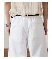 White wide-leg shorts with a relaxed fit, shown from the back on a model wearing a beige striped shirt and a black belt. 