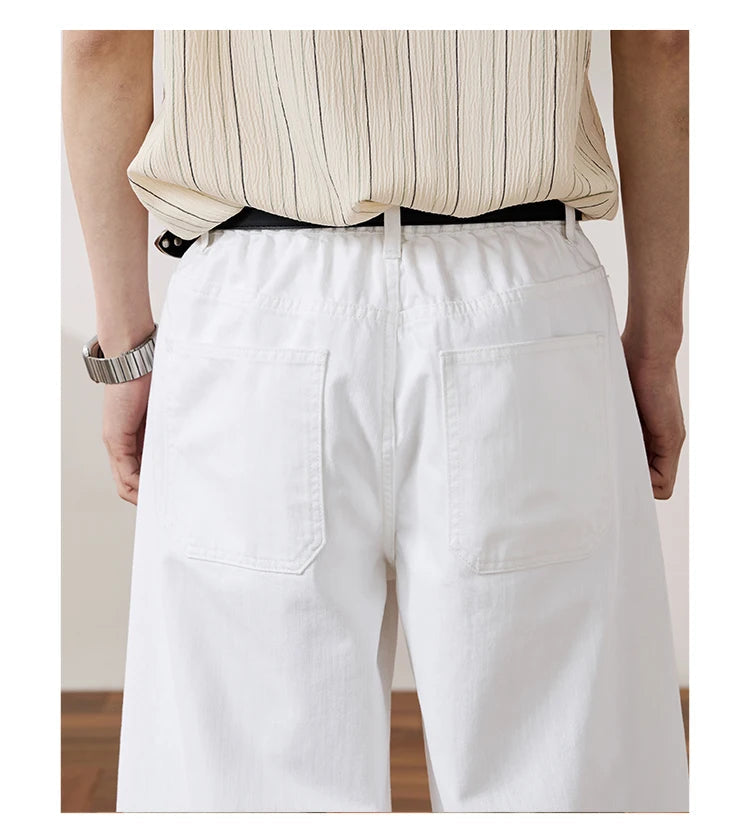 White wide-leg shorts with a relaxed fit, shown from the back on a model wearing a beige striped shirt and a black belt. 
