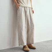 Person wearing beige wide-leg pants and shoes against a plain background