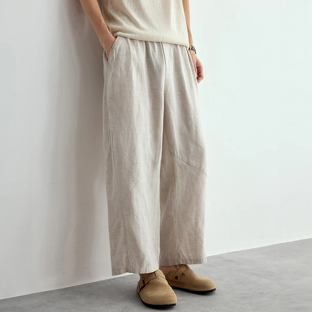 Person wearing beige wide-leg pants and shoes against a plain background