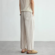 Person wearing beige sleeveless top and wide-leg pants on a plain background