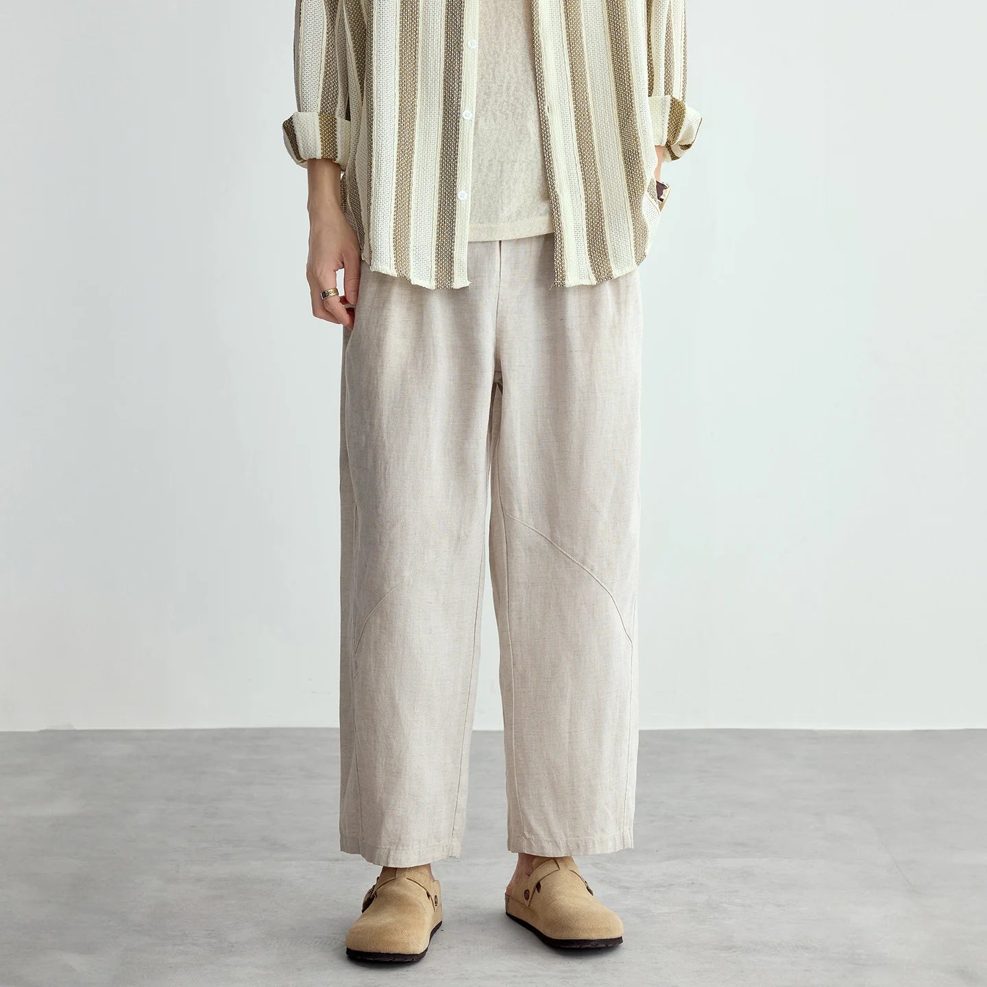 Person wearing a striped shirt and beige pants on a plain background