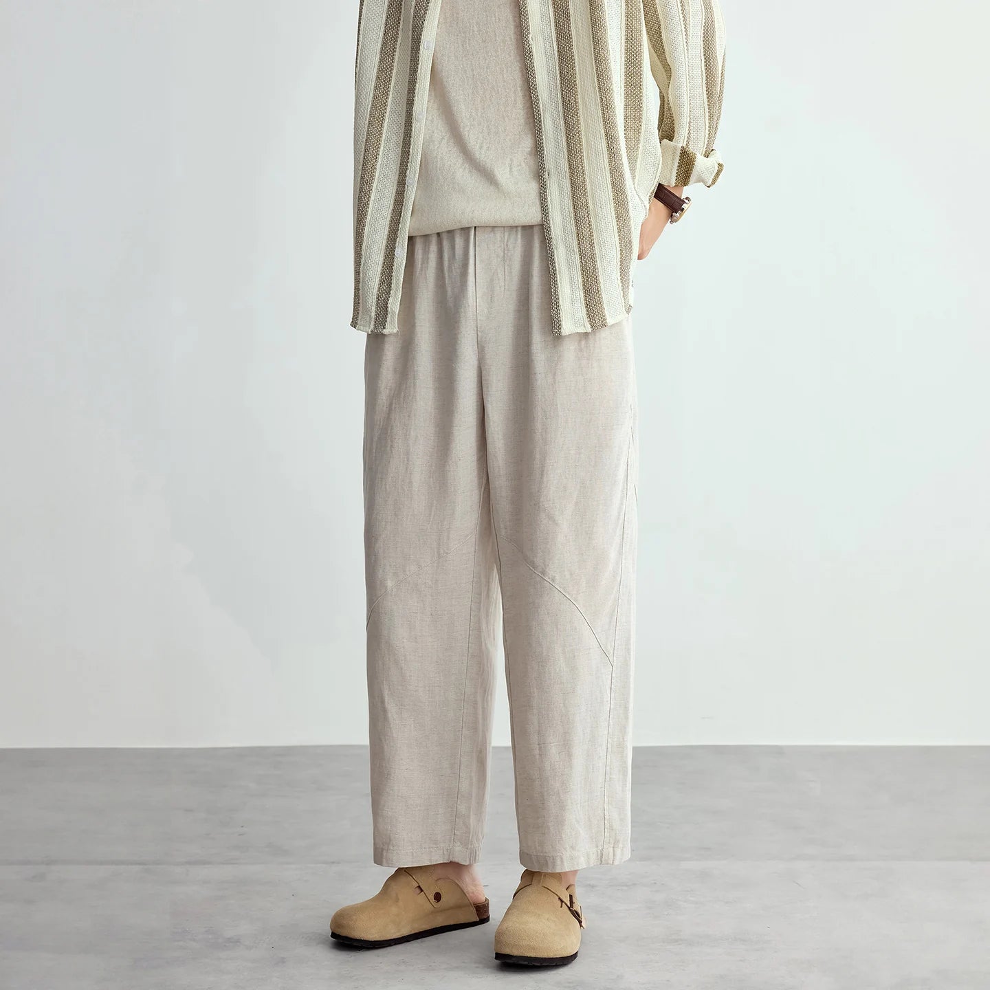 Person wearing beige pants and a striped shirt against a plain background