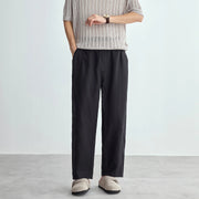 Person wearing a striped shirt and black pants on a plain background