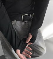 Person wearing a black shirt and gray pants with a belt, on a neutral background.