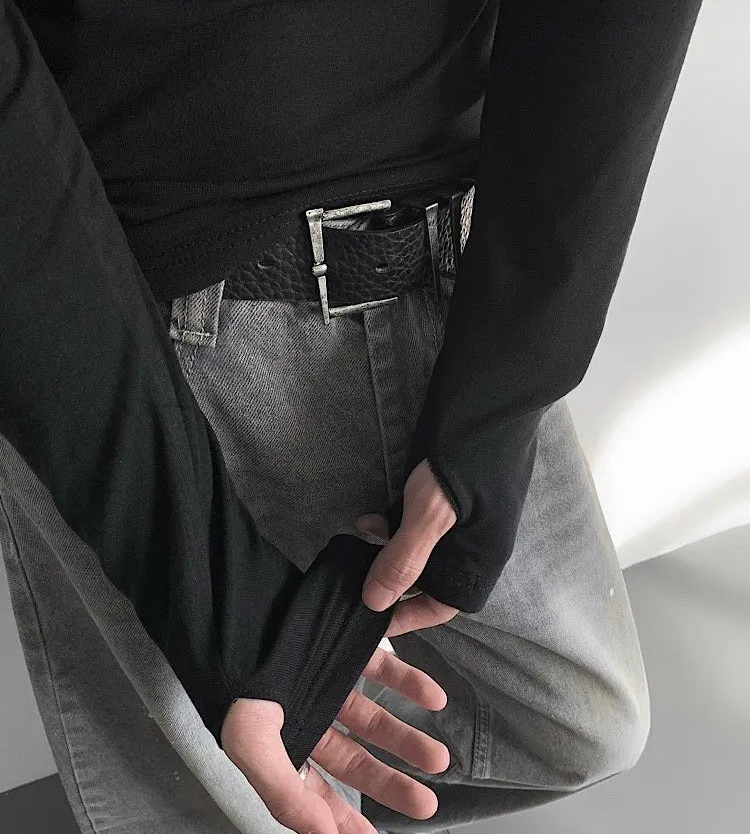 Person wearing a black shirt and gray pants with a belt, on a neutral background.
