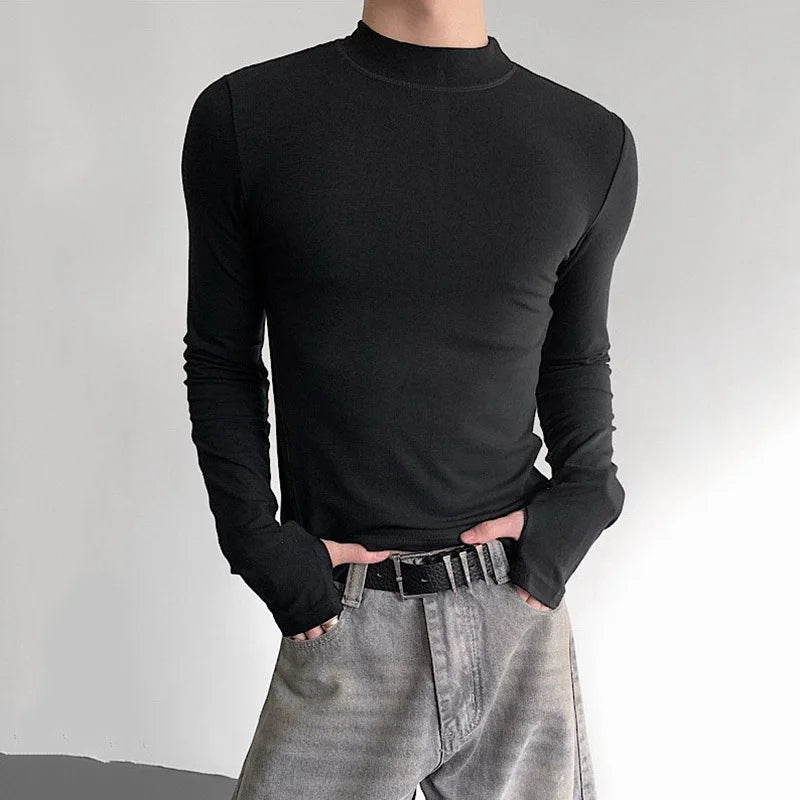 Person wearing a black long-sleeve shirt and light gray pants against a plain background