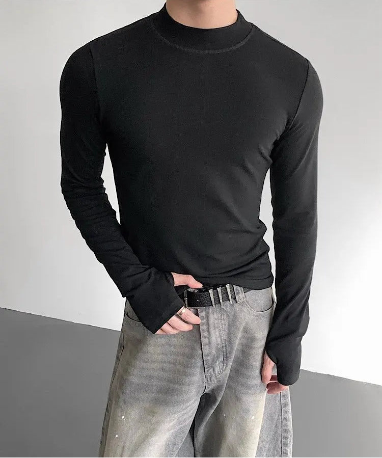 Person wearing a black long-sleeve shirt and gray jeans against a neutral background