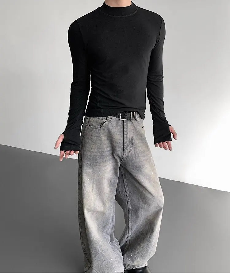 Person wearing a black long-sleeve shirt and light gray pants on a gray background