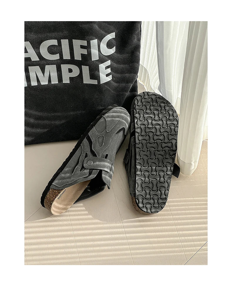 Black slippers with textured sole on a light-colored floor, wearing a black garment with 'PACIFIC SIMPLE' text.