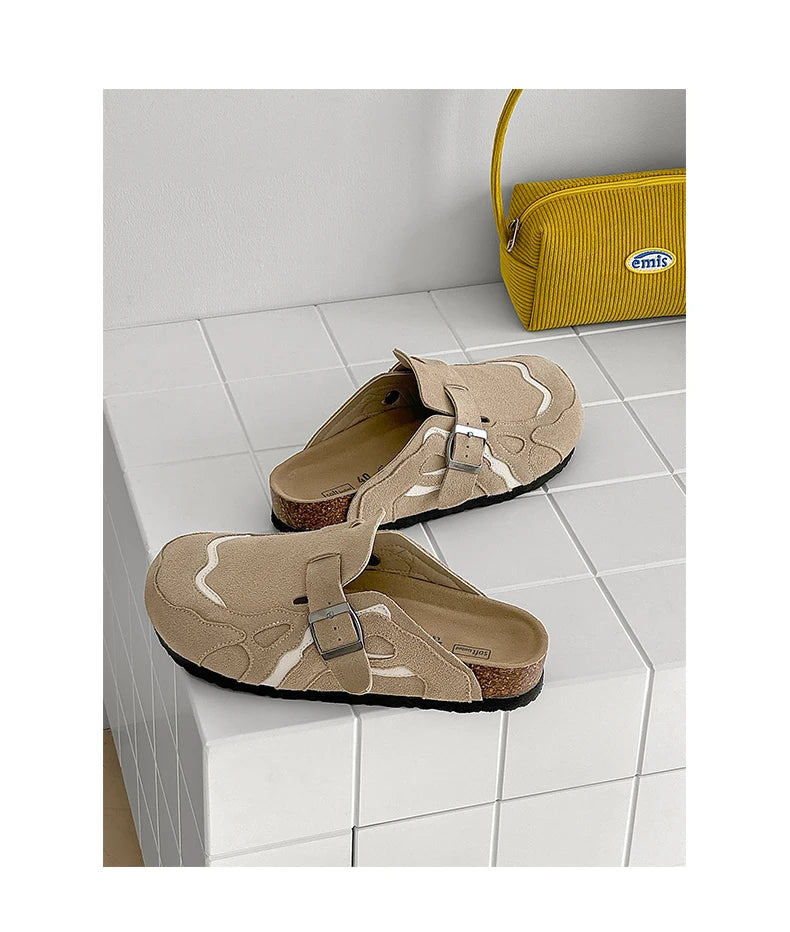 Pair of beige sandals with a strap on a tiled floor next to a yellow bag.