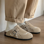 Beige suede shoes with buckles worn indoors on a wooden floor.