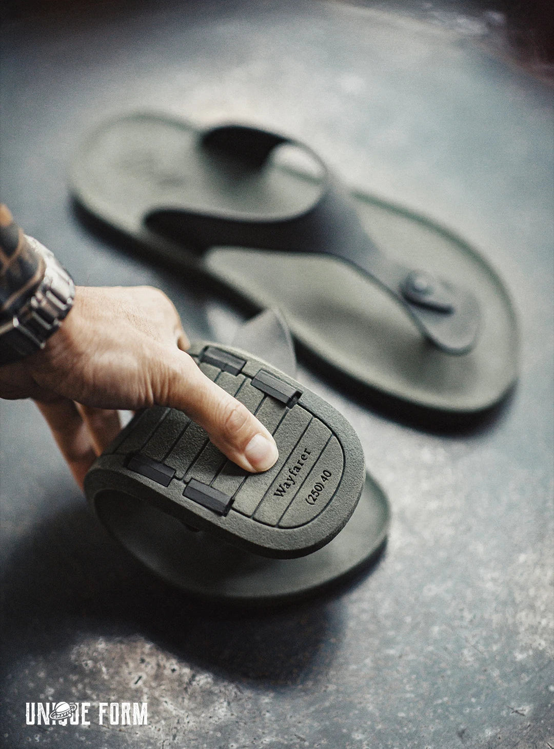 Person holding a sandal insole with 'Unique Form' branding on a dark surface
